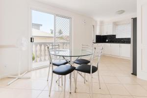 a dining room with a glass table and chairs at Redcliffe Villa in Redcliffe