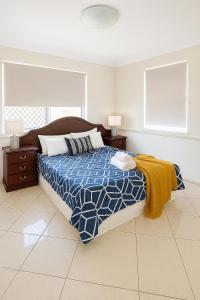 a bedroom with a bed with a blue and white comforter at Redcliffe Villa in Redcliffe