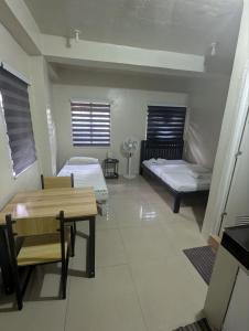 a room with two beds and a table and chairs at Casa Feliz Apartments Baguio in Baguio