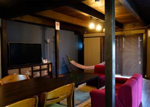a living room with a table and chairs and a tv at マホロバハウス ペットも泊まれる1棟貸 in Tadotsu