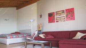 a living room with a red couch and a bed at Casa Guglielmo in Pisogne