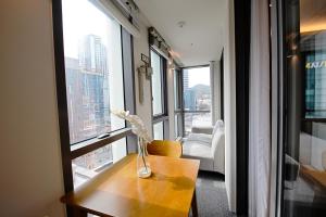 a vase of flowers on a table in a room with windows at RUNA Stay HAEUNDAE in Busan