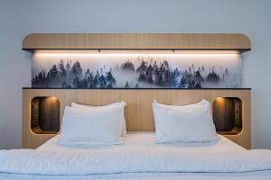 a bed with white pillows and a picture of trees at Q Resort and Spa in Săcele