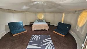a bedroom with two blue chairs and a bed in a tent at DGG Woodland Escape in South Barrow +84 photos