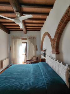 a bedroom with a large bed with a ceiling fan at Il Peppolo Country House in Pelago