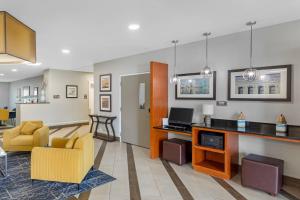 a living room with a couch and a desk with a television at Comfort Suites West Jacksonville in Jacksonville