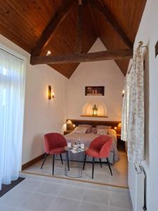 a bedroom with a bed and two red chairs at Le Manoir de Placy - Chambres d'Hôtes in Clécy +37 photos
