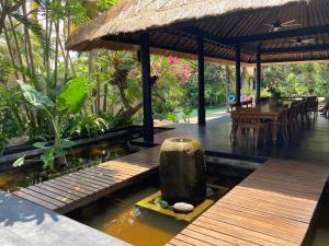 a pavilion with a table and a wooden deck with a pond at Villa Rawarawa Private Beachfront in Central of Lovina by GEMA MANAGEMENT BALI in Lovina