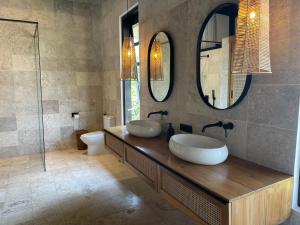 a bathroom with two sinks and two mirrors at Villa Rawarawa Private Beachfront in Central of Lovina by GEMA MANAGEMENT BALI in Lovina