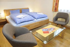 a bedroom with a bed and two chairs and a table at Gästehaus Maria Trattner in Mauterndorf