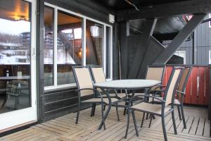 a table and chairs on a porch with windows at Stølstunets samlingssted in Beitostøl
