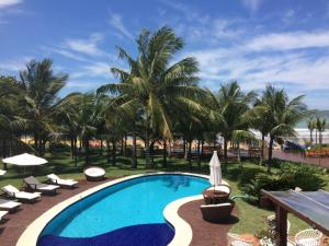 - une piscine avec des chaises longues et des palmiers dans l'établissement Espelho das Águas Búzios, à Búzios