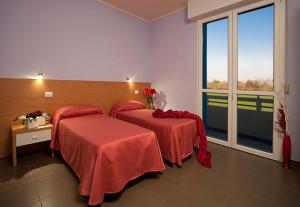 a hotel room with two beds and a large window at Hotel Ponte in Colorno
