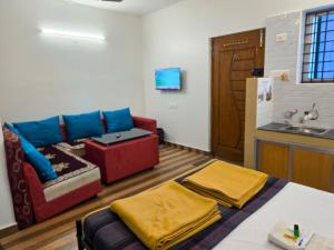 a living room with a couch and a kitchen at Chithralaya Guest House in Yercaud