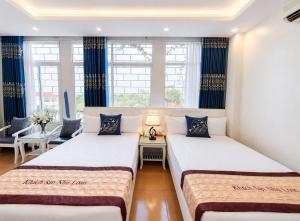 two beds in a room with blue curtains at Hotel Nhu Loan in Bạch Ðoài