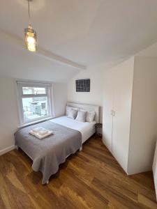 a white bedroom with a bed and a window at Literally Central Brighton Sleeps 8 in Brighton & Hove