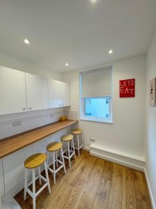 a kitchen with white cabinets and stools at Literally Central Brighton Sleeps 8 in Brighton & Hove