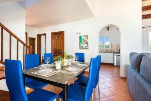 a dining room with a table and blue chairs at Villa Vientosol by Villa Plus in Cala en Forcat