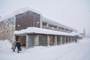 two people walking in the snow in front of a building at Hotel Lavenir in Biei