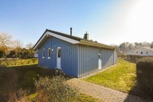 a small blue house with a grass yard at Ferienhaus Strandpark 41 in Grömitz