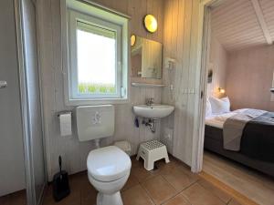 a bathroom with a toilet and a sink and a bed at Ferienhaus Strandpark 13 in Grömitz