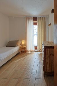 a bedroom with a bed and a table and a window at Rifugio Baita Belvedere in Champoluc