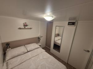 a small bedroom with a bed and a mirror at Glamour Pakoštane Mobile Home in Pakoštane