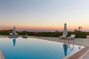 a swimming pool with two lawn chairs and umbrellas at Belvedere Beachfront Villa in Afantou