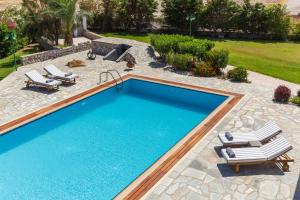 a swimming pool with two lounge chairs and a patio at Belvedere Beachfront Villa in Afantou