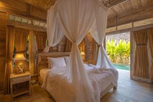 a bedroom with a bed with a mosquito net at Wana Shanti Villa in Bringkit