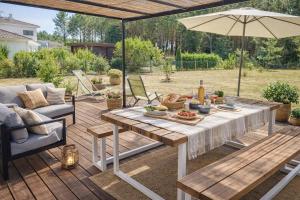 a wooden deck with a table and an umbrella at Élégance et nature votre refuge entre mer et forêt in Vielle-Saint-Girons
