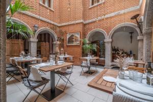 a patio with tables and chairs and a brick wall at Casona De Torres in Mondéjar