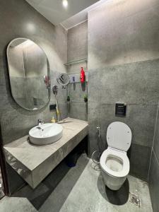 a bathroom with a toilet and a sink and a mirror at Shagun Stays in Greater Noida