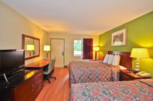 a hotel room with two beds and a desk and a television at Country Hearth Inn & Suites Marietta in Atlanta