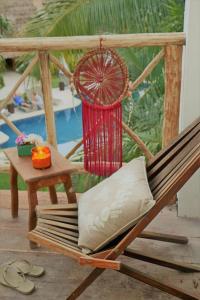 a hammock chair with a red umbrella and a table at WishTulum in Tulum