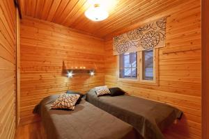 two beds in a room with wooden walls at Levin Kalle Apartment in Levi