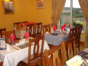 ein Esszimmer mit Tischen und Stühlen mit roten Blumen darauf in der Unterkunft Rosmo House B&B in Westport