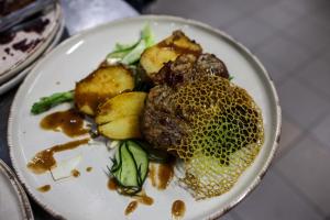 a plate of food with meat and vegetables on a table at Resita Residence Hotel in Reşiţa