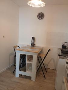 a table and chairs in a kitchen with a clock on the wall at Le cocon en Champagne in Avize