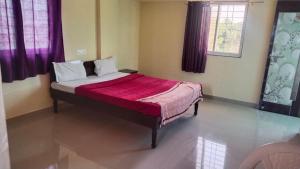 a bedroom with a bed with a red blanket at jAYESH PALACE in Loni Kālbhor