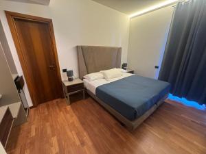 a bedroom with a bed with blue sheets and a wooden floor at Hotel Baia Flaminia in Pesaro