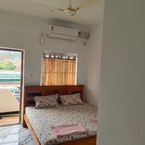a bedroom with a bed and a window with a fan at Durga Residency in Alāndurai
