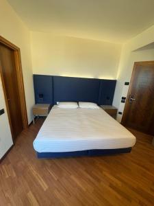 a bedroom with a large bed with a blue headboard at Hotel Baia Flaminia in Pesaro