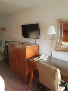 a hotel room with a desk with a television and a chair at Masters Inn I-26 in Cayce