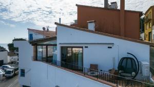 a white building with a balcony with a car on it at Seamount, studio 3 mins from Tamariu beach in Tamariu