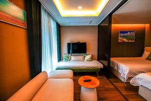 a room with two beds and a couch and a table at RUNA Stay HAEUNDAE in Busan