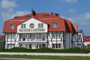 a white and red building with a red roof at Przystań u Kapitana in Ustka