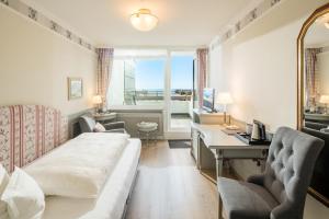 a hotel room with a bed and a desk and a window at Hotel Wiking Sylt in Westerland