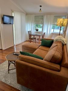 a living room with a brown couch and a table at Lemon Cottage in Rous Mill