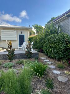 a house with a patio with a white chair and plants at Lemon Cottage in Rous Mill